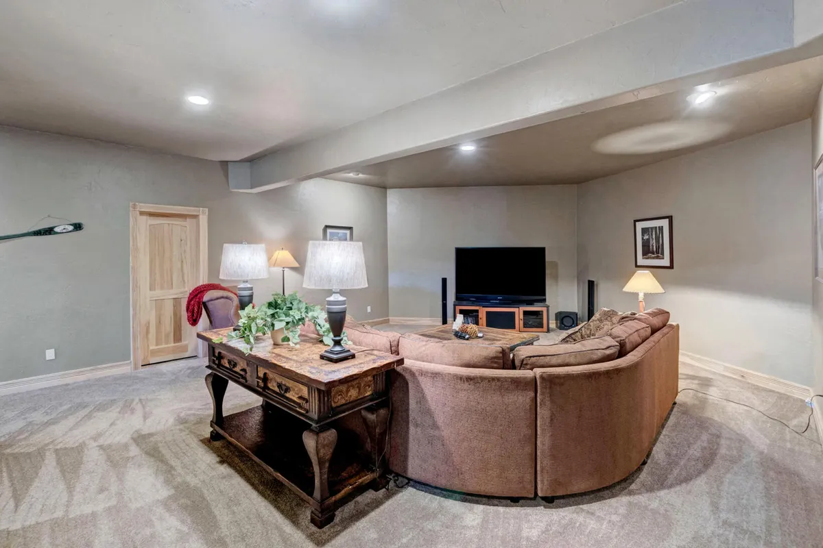A welcoming living space featuring a comfortable sofa, a coffee table set for board games, a large flat-screen television as the focal point, and soft lamp lighting. The ambiance is relaxed and ideal for entertainment or intimate gatherings.
