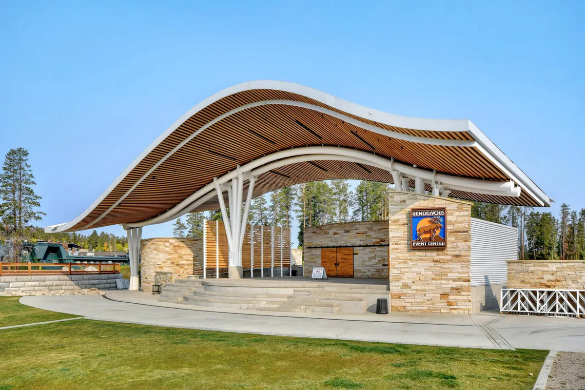 A modern, open-air amphitheater with a curved roof, stone walls, and ample event space. The setting is designed for community concerts, family events, and local celebrations under the open sky.