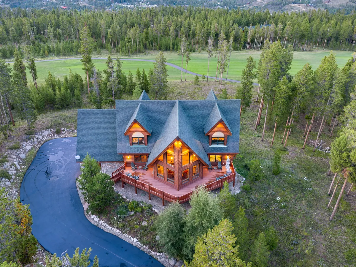 This exterior showcases the large wooden deck of the home, distinctive house architecture, and the surrounding trees. The winding driveway and ample outdoor seating suggest a welcoming space for barbecues, family gatherings, or simply relaxing amid nature, echoing the sense of privacy and exclusivity described in the section.